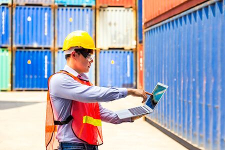 Foreman or Operator Ordering of moving containers with laptop computer. Foreman looking forward on Forklifts in the Industrial Container Cargo freight ship.の写真素材