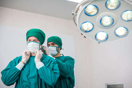 The surgeon was wearing a surgical mask on a colleague in the operating room.の写真素材