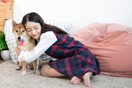 An Asian woman lovingly hugs the Shiba Inu. Dog and girl in the living room.の写真素材
