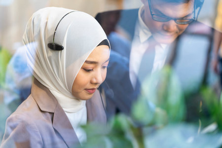 Muslim call center staff. The customer service manager is assisting the call center clerk to provide customer support services. The young call center is working to answer customer questions. Traineeの写真素材