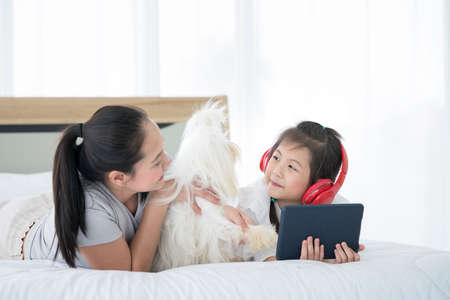 A mother whose daughter is using a laptop computer and has a Shiba Inu on the sofa. Space for Text.