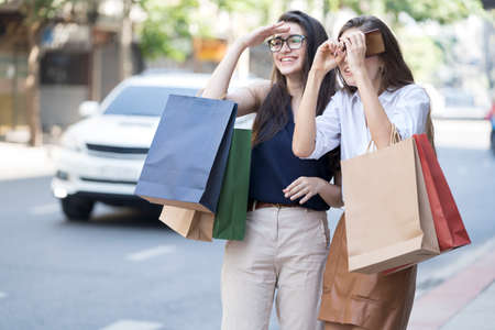 Young women and shopping bags. Happy woman paying in cafe by credit card and smart phone. Two young woman chatting in a coffee shop.の写真素材