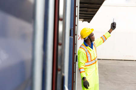 Import and Export concept. Foreman using laptop computer in the port of loading goods. Businessman with safety equipment working at warehouse.の写真素材