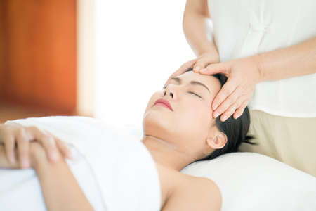 A young Asian woman getting a head massage It's in a spa shop. Young Asian girl relaxing with hand spa massage at beauty spa salon.の写真素材