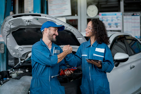 Smallbusiness. Two happy auto mechanics in uniforms working in auto service with car. Two men...