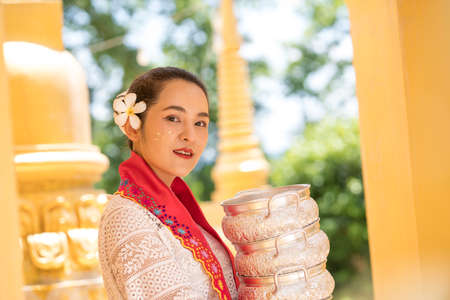 Myanmar women holding flowers at a temple. Southeast Asian young girls with burmese traditional dress visiting a Buddihist temple.の写真素材