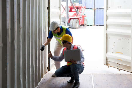 Foreman using laptop computer in the port of loading goods. Foreman operator ordering of moving...