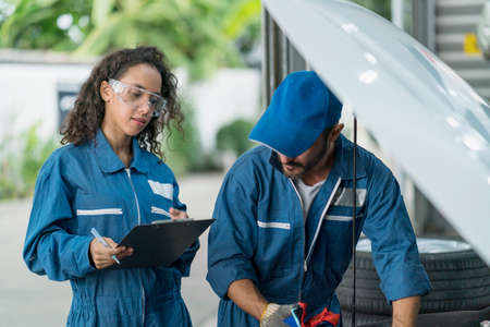 Auto services concepts. Auto mechanic male and female with automotive diagnostic scanner and...
