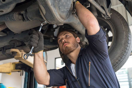 A car mechanic repairing the brakes and shock absorber. Car brake repairing in garage. Auto mechanic...