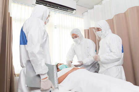 Asian doctor is taking care patient woman in hospital. Doctor with stethoscope analyzing patient data. Doctors checking patients in a controlled area, state quarantine.の写真素材