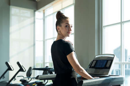 Fit women doing cardio workout and running on treadmill in sport club.