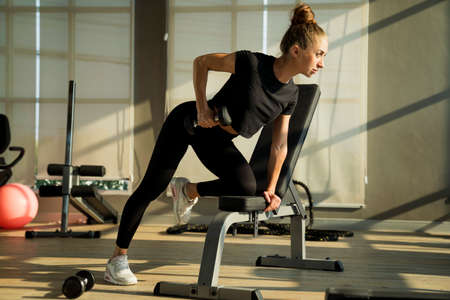 Concept fitness sport training lifestyle. Young woman lifting dumbbells. Active sport athletic woman with dumbbells pumping up muscles body.の写真素材