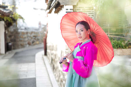 Korean girl wearing a hanbok wearing Pink umbrella. The famous palaces in Seoul. Beautiful Female...