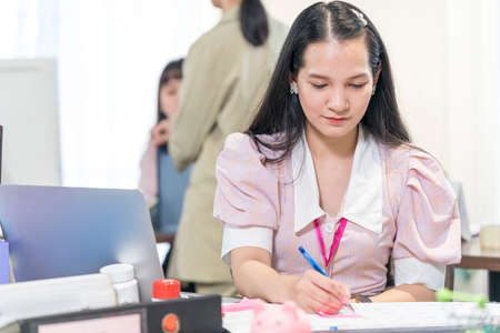 Young female staff working on a planner on a desk in a small company.の写真素材