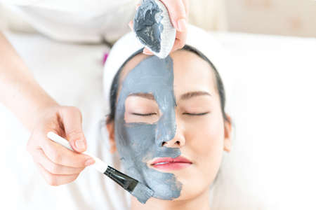 Woman with facial mask in beauty spa. Beautician doing facial mask.
