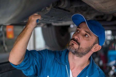 Mechanic man with clipboard checking car system at workshop. mechanic man or smith repairing car at garage.の写真素材