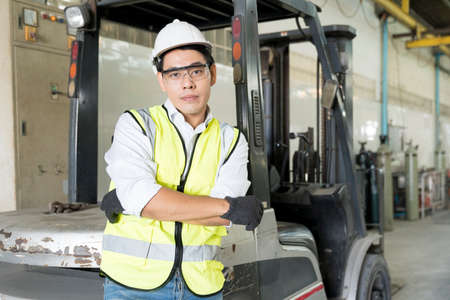 Foreman or technician standing with a forklift parked in the factory.の写真素材