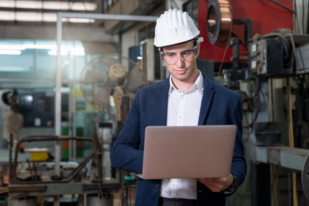 Engineers and skilled technicians are maintaining machinery. Professional technicians are using a laptop computer to control work in industrial plants.の写真素材