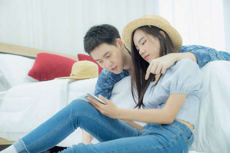 Couple planning a trip with a tablet in the bedroomの写真素材