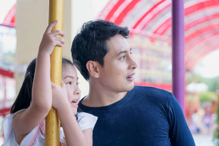 Father and daughter playing rides in the amusement parkの写真素材