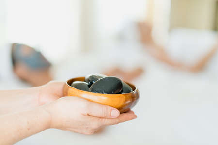 Spa staff holding hot stones for spa treatmentの写真素材