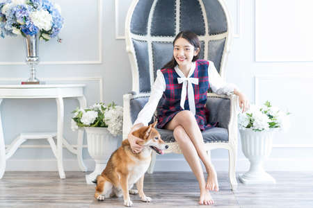 A young Japanese woman is sitting with a Shiba Inu in the living room. Young female looking camera.の写真素材
