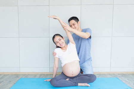 Dad is helping pregnant mothers exercise. And doing yoga in the living roomの写真素材