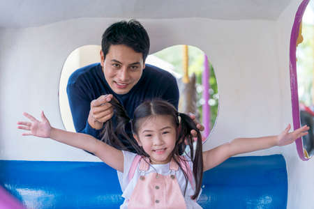 Family in theme park. Father and girl in an amusement park. Father and daughter looking camera near carousel in amusement park.の写真素材