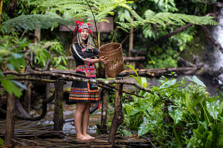 Hmong hill tribe clothes. A young hill tribe woman is walking on the water on the waterfall.の写真素材