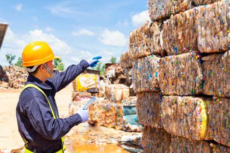 An employee at a recycling plant is pointing to plastic waste being sent to the recycling process. Engineer looking and pointing forward.の写真素材