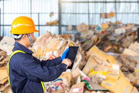 Engineer in a paper recycling plant. Employees in a paper recycling plant use a tablet.の写真素材