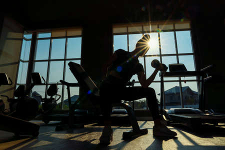 Silhouette, Woman are playing dumbbells to build muscle. Muscular young female exercising with dumbbells.の写真素材