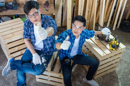 Wood mechanic doing furniture in a furniture factory. A carpenter is holding a thumbs up in the workshop.の写真素材