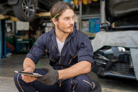 Service repair maintenance concept. Auto mechanic are resting and using tablet computer.の写真素材