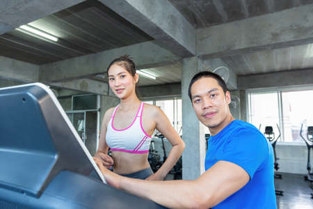 A young woman works on a treadmill in a fitness center. Fitness center young woman exercise with personal trainer on gym machine.の写真素材