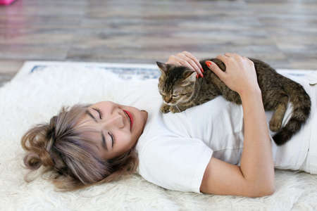 Asian women are playing with cats in the living room.の写真素材