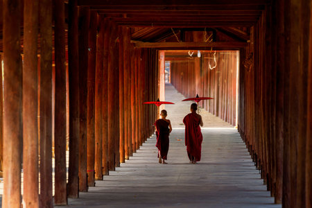 A monk holding an umbrella walks in a temple with a wooden walkway at Bagan in Myanmar on Jan 26, 2021.のeditorial素材