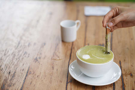 Hot green tea served with cinnamon on hand.の写真素材