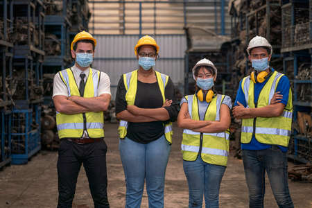 Portrait of warehouse worker. Group of factory industry worker working with face mask to prevent virus spreading during job reopening period.の写真素材