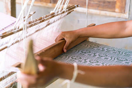Traditional Isan Thai cotton weaving. old woman hand weaving cotton in traditional way at manual loom. Loei, Thailand.の写真素材