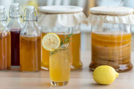 Kombucha tea with lemon and sweetened root filling in glass jug on kitchen background. Natural kombucha fermented tea beverage healthy organic drink in glass.の写真素材