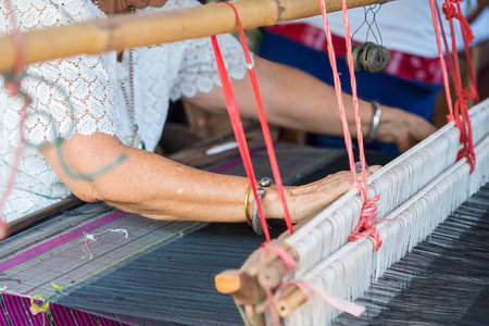 Traditional Isan Thai silk weaving. old woman hand weaving silk in traditional way at manual loom.の写真素材