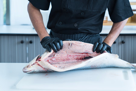 Japanese chef cleaning salmon. A worker cutting salmon on a board.
