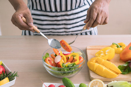 The concept of a healthy diet and lifestyle. Man is preparing a salad of various vegetables in the kitchen.の写真素材