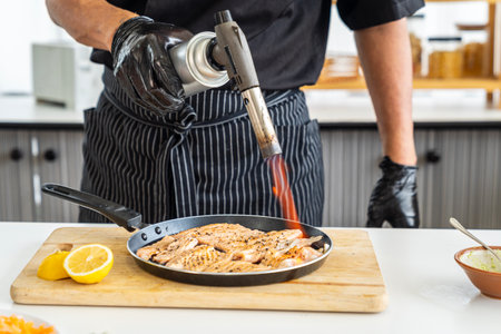 Japanese Chef sprinkle salt on salmon meat. Japanese Cuisine food, using gas burner torch.の写真素材