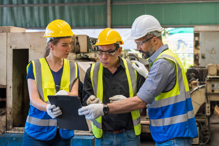 Factory workers working and discussing in factory. Foreman and engineer holding clipboard. Group of technicians or foreman.の写真素材