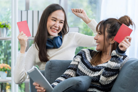 Concept of travel in summer and holiday. Two Asian woman planning a trip and holding a passport in the living room.の写真素材