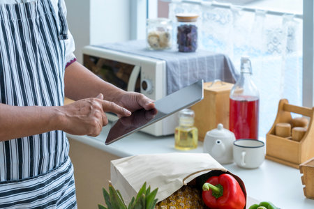 Male hands with digital recipe. Healthy salad on digital tablet. Vegetable and Shopping bag.の写真素材
