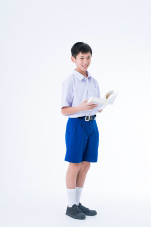 Back to school. Thai students. The boy standing and reading a book.の写真素材