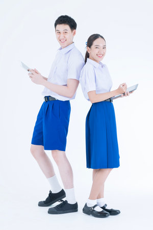 Back to school. Thai students. The boy and girl standing and using digital tablet.の写真素材